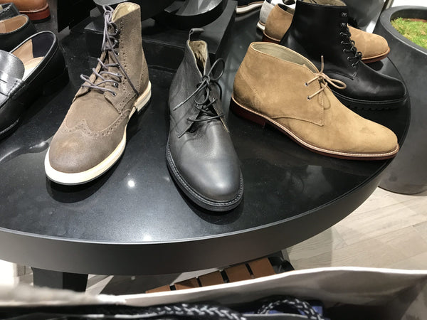 A round table with different styles of mens lace up shoes.