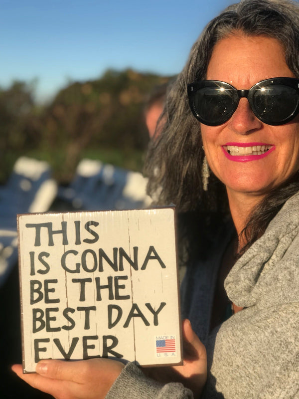 smiling woman holding a sign that says, this is gonna be the best day ever